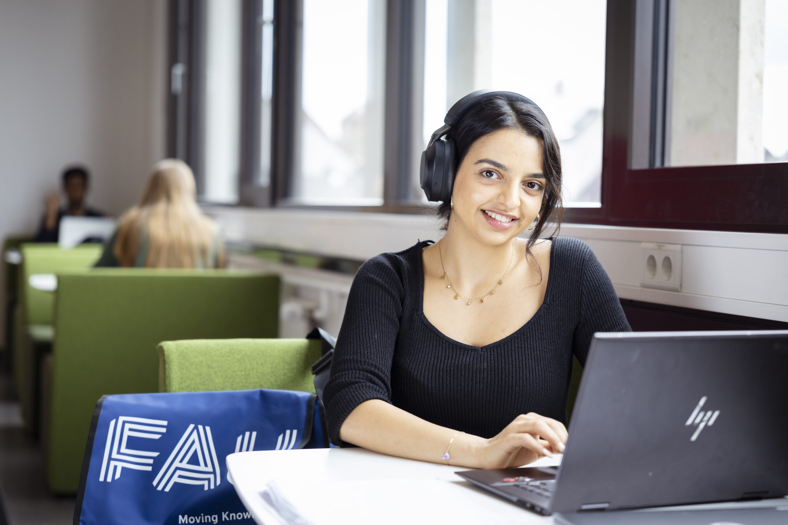 Person mit Kopfhörern blickt vom Laptop auf